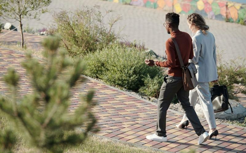 A man and woman walking on a brick sidewalk.